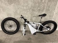 White e-bike frame laid on ground with two fat-tire wheels and front suspension fork