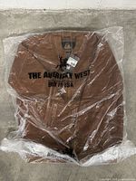 Full view of the sealed tan leather bomber jacket by American West in plastic packaging with printed branding.