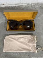 Photo of Bvlgari sunglasses inside the open hard case with accompanying soft drawstring pouch laid out