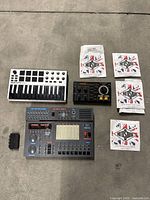 Top-down view of entire lot including MIDI controller, drum machine, trainer board, battery holder and string packets