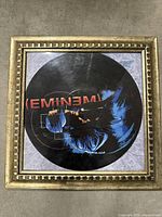 Framed vinyl record with Eminem image printed on the record and gold-colored frame