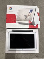 Google Nest Hub device in its original box with wear on the packaging.
