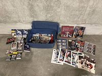 Wide view of bin, sealed packs, tins, books, photos spread on floor