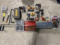 Overall layout of lot on concrete floor showing hand tools, power tools, storage cases and hardware boxes.