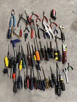All items laid out on floor showing variety of screwdrivers, pliers, wrenches, and other hand tools