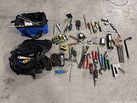 Top-down view of the lot with tools laid out beside two open tool bags showing pliers, screwdrivers, wrenches, clamps, hand drill, tape measure, and other hand tools.