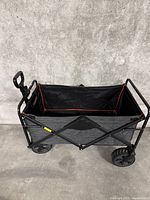 Side top view of folding utility moving cart showing the black fabric interior with red trim and metal frame.