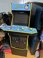 Front left view of the Arcade1Up The Simpsons cabinet showing marquee, screen, control panel, and lower coin door.