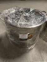Photo of 20 quart stainless steel stock pot wrapped in plastic with lid on.