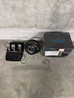 Wheel, pedal set, and original box arranged on concrete floor