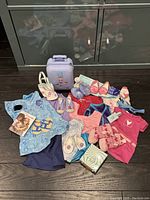 Overview of American Girl doll accessories and clothing including suitcase, shoes, dresses, mittens, book