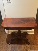 Front view of closed flip-top end table showing rectangular top and carved pedestal base