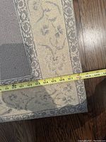 Section of rug showing outer border pattern and tape measure across width