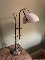 Side view of the vintage desk lamp showing metal base, vertical rods, and white glass shade with black electrical cord.