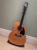 Full front view of guitar showing dreadnought cutaway body and natural wood finish