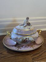 Full view of covered tureen set on matching platter showing handles, lid, and side compartments