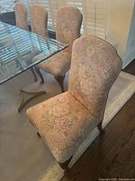 Group view of five chairs around glass table showing upholstery and frame style