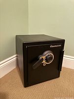 Front exterior view of black SentrySafe safe closed, showing dial, handle and logo