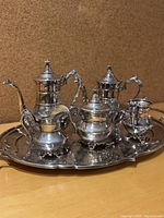 Front angled view of the entire silver plate tea service including tray with all items grouped closely, showing detailed design in natural light.