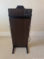 Full view of electric trouser press showing wood grain finish and metal handles.