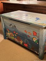 Side and front view of wooden toy chest showing colorful under the sea themed handpainted fish, crab, seaweed, and coral.