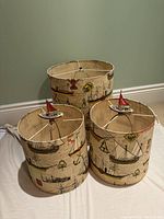 Three cylindrical lamp shades with nautical vintage ship print and boat finials, showing two medium and one large shade.