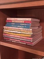 Stack of 11 vintage Walt Kelly authored Pogo books with visible titles and publisher Simon and Schuster.