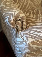 Close-up of chair arm and nailhead trim showing zebra print upholstery detail