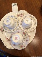 Photo showing the undersides of three Royal Albert teacups and saucers placed on the Lavender Rose platter, revealing the markings and floral details.