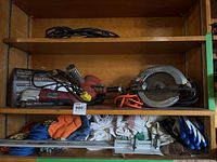 Wide view of wooden shelves showing the Chicago Electric oscillating multi-function power tool, Skilsaw circular saw, heat gun, assorted rags, rope, and extension cord.
