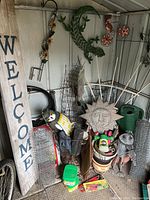 Overview of garden decor and tools including 'WELCOME' sign, metal animal and floral stakes, sun face decoration, pots, and garden supplies.