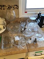 View of the full collection including a large vase/bowl, divided serving tray, round serving bowl, pedestal dish, salt and pepper shakers.