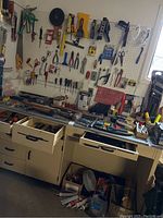 Overview of pegboard and bench with assorted hand tools hung and laid out