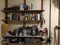 Photo of shelves with assorted bottles, cans, and cleaning supplies including sponges and hardware boxes