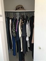 Closet rail with assorted ladies clothing including blouses, skirts, and culottes hung on hangers, sizes mostly medium and large.