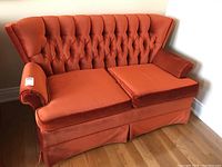 Full view of the retro orange velour love seat showing overall condition and design.