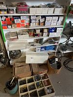 Shelving unit with multiple bins and boxes containing assorted hardware including nails, screws, and small hardware boxes