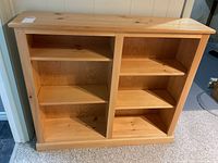 Front view of pine wood bookcase showing divided shelves with triangular honeycomb style shelves on the left and rectangular shelves on the right.