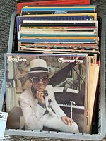 Top down photo showing a stack of vintage vinyl albums with Elton John Greatest Hits as the front record.