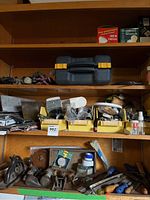 Wide view showing shelves with antique wood planers, files, extension cords, brushes, and miscellaneous hand tools and parts in trays.