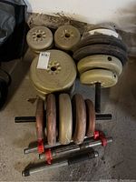 Overhead view of white and brown barbell weight plates stacked on poles, showing wear and some dirt.