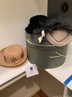 Photo showing the three hats and hatbox together on a shelf.
