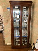 Full front view of the wooden china hutch showing glass doors and interior glass shelves, filled with display items (not included in sale).