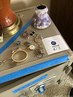 Photo of all jewelry items and clay vase displayed on grey surface.