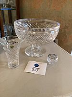Large crystal punch bowl, 6-inch Waterford vase, and crystal bud bowl with silver flower holder on table.