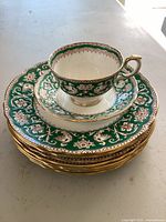 Stacked green and gold trimmed teacups and saucers from Spode (Ellesmere)