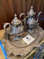 Photo of the full coffee service set including the large ornate tray and two decorated coffee pots with bird-shaped handles and finial lids.