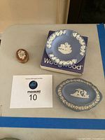 Overall view of three items: blue Wedgwood ashtray on box, blue oval decorative piece, and small orange trinket box.