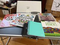 Front view of coloring books, colored pencils, markers, spiral notebooks, and lap table, all laid out on the lap table surface.