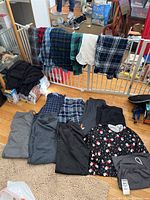 Flannel shirts hanging over a baby gate and sweatpants laid on floor.